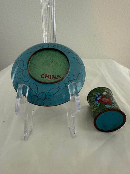 Small ceramic plate and cup with floral designs on a white surface.