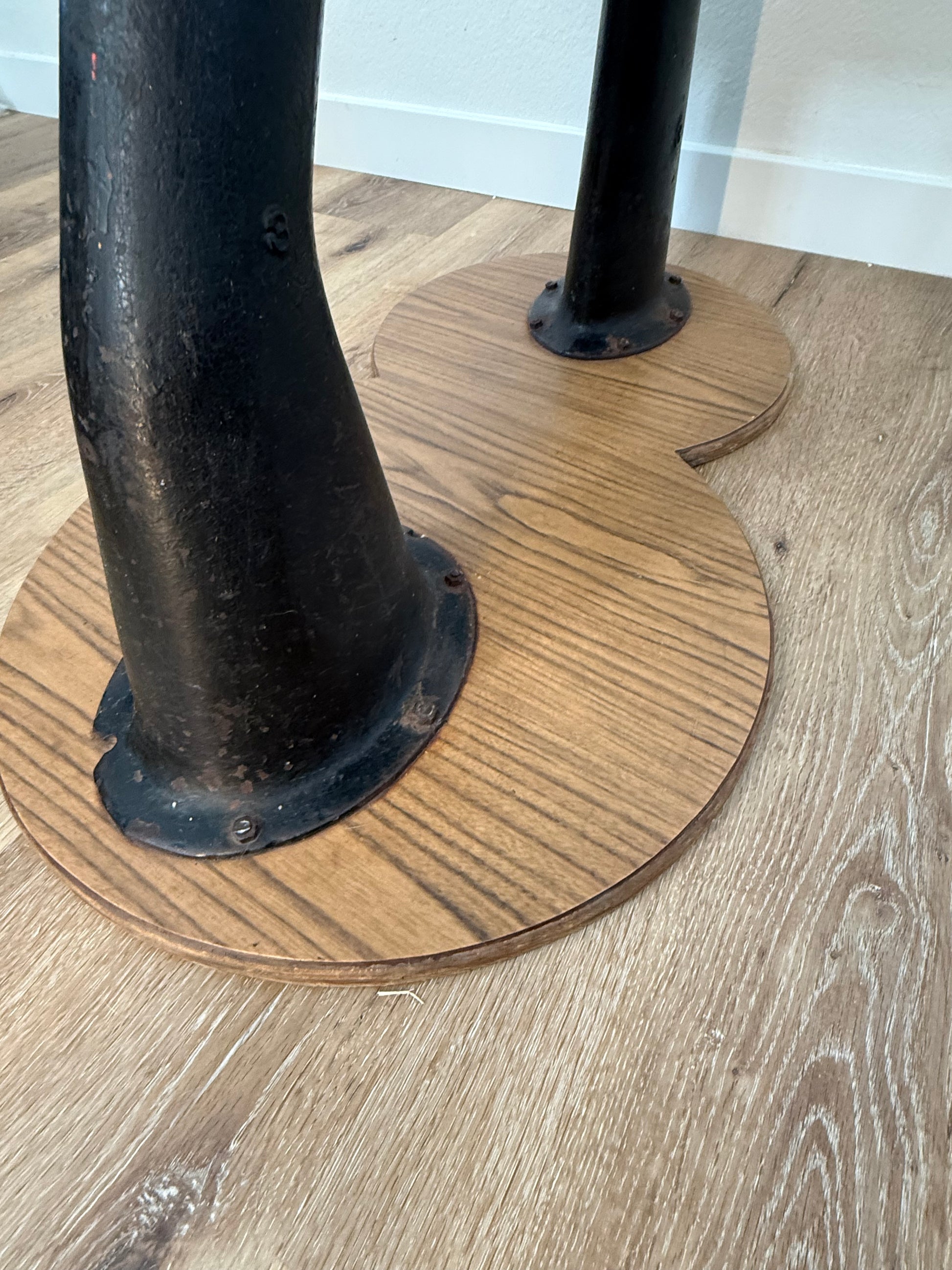 Wooden chair seat with a cast iron leg on a wooden floor