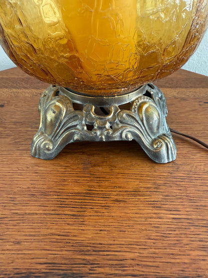 Decorative amber glass ornament with intricate metal fixture on a wooden surface