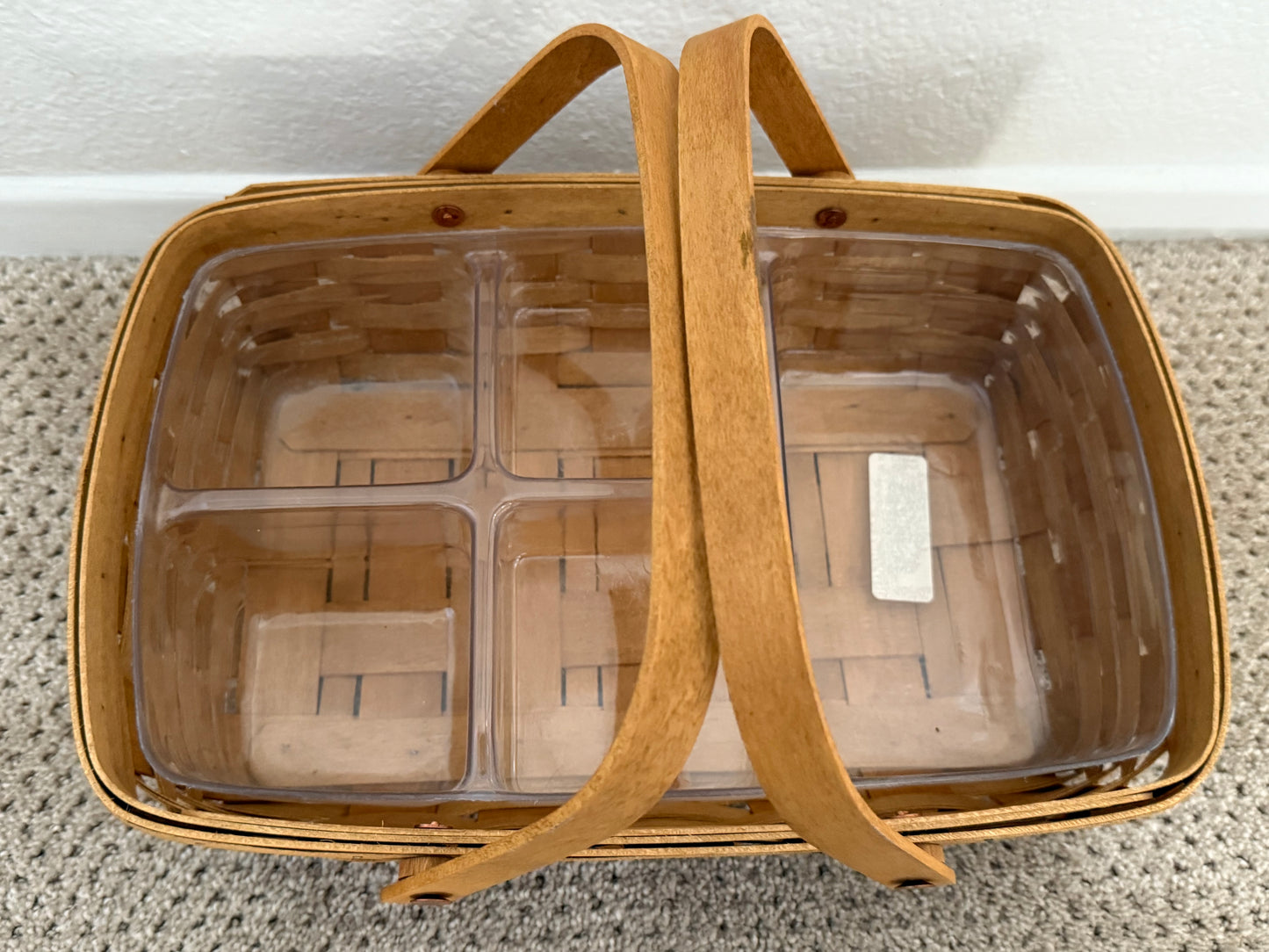 Basket with clear compartments and brown handles on a light background