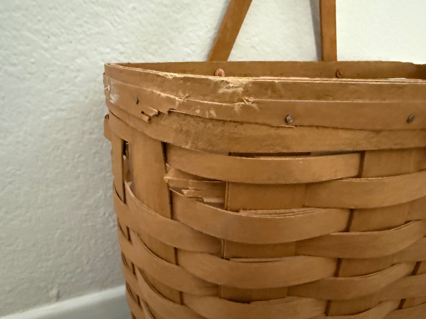 Close-up of a woven brown basket against a white wall