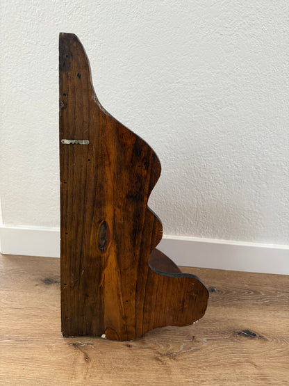 Wooden shelf sitting on a wood floor with white wall in the background.