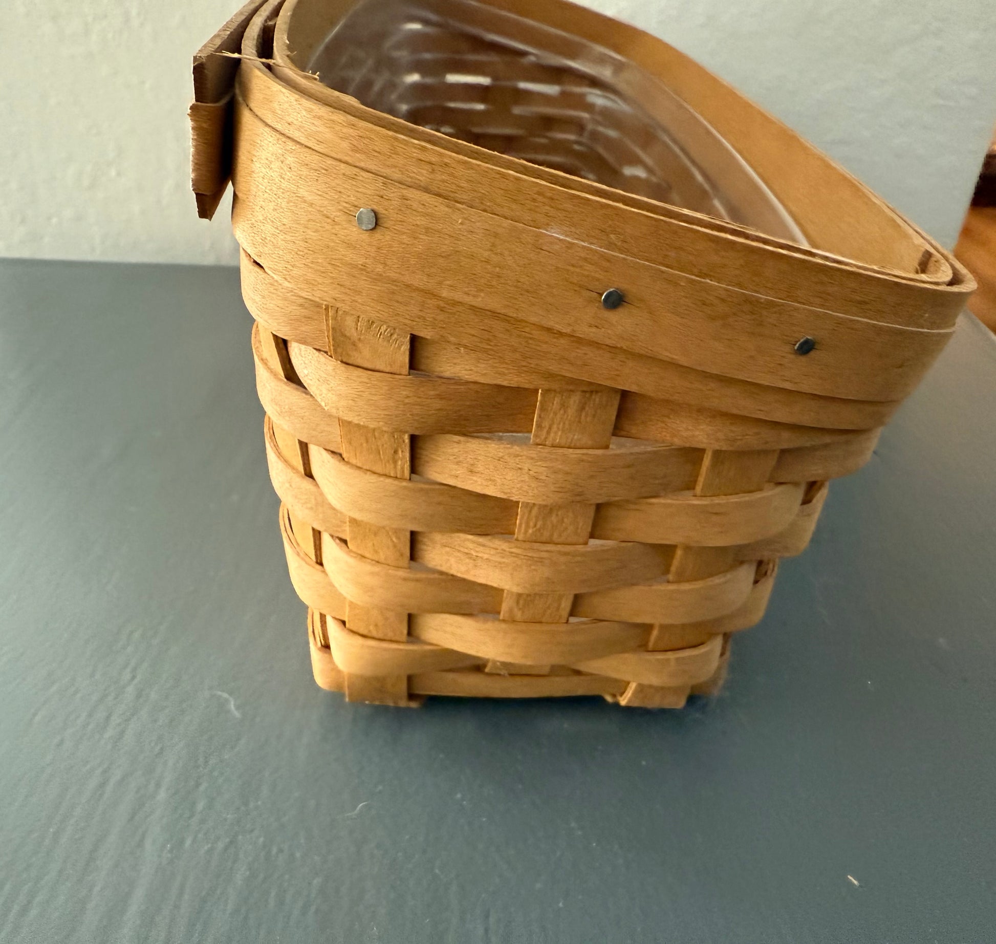 Woven basket with a clear plastic liner on a gray surface