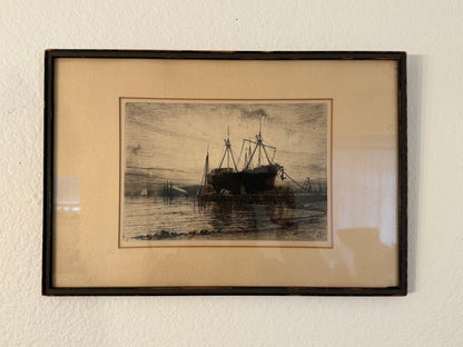 Framed black and white print of a ship on water against a beige wall.