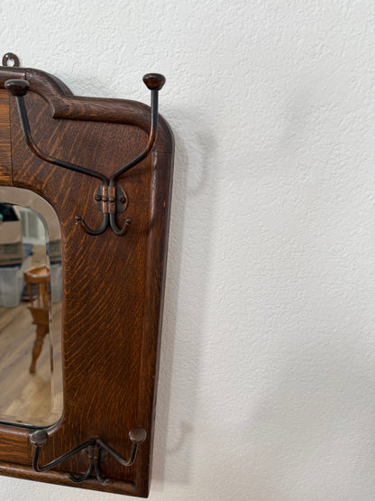Tiger wood wall-mounted mirror with metal hooks on a textured white wall