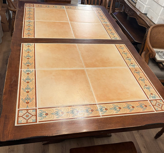 Wooden table with decorative tile pattern on a wooden floor.