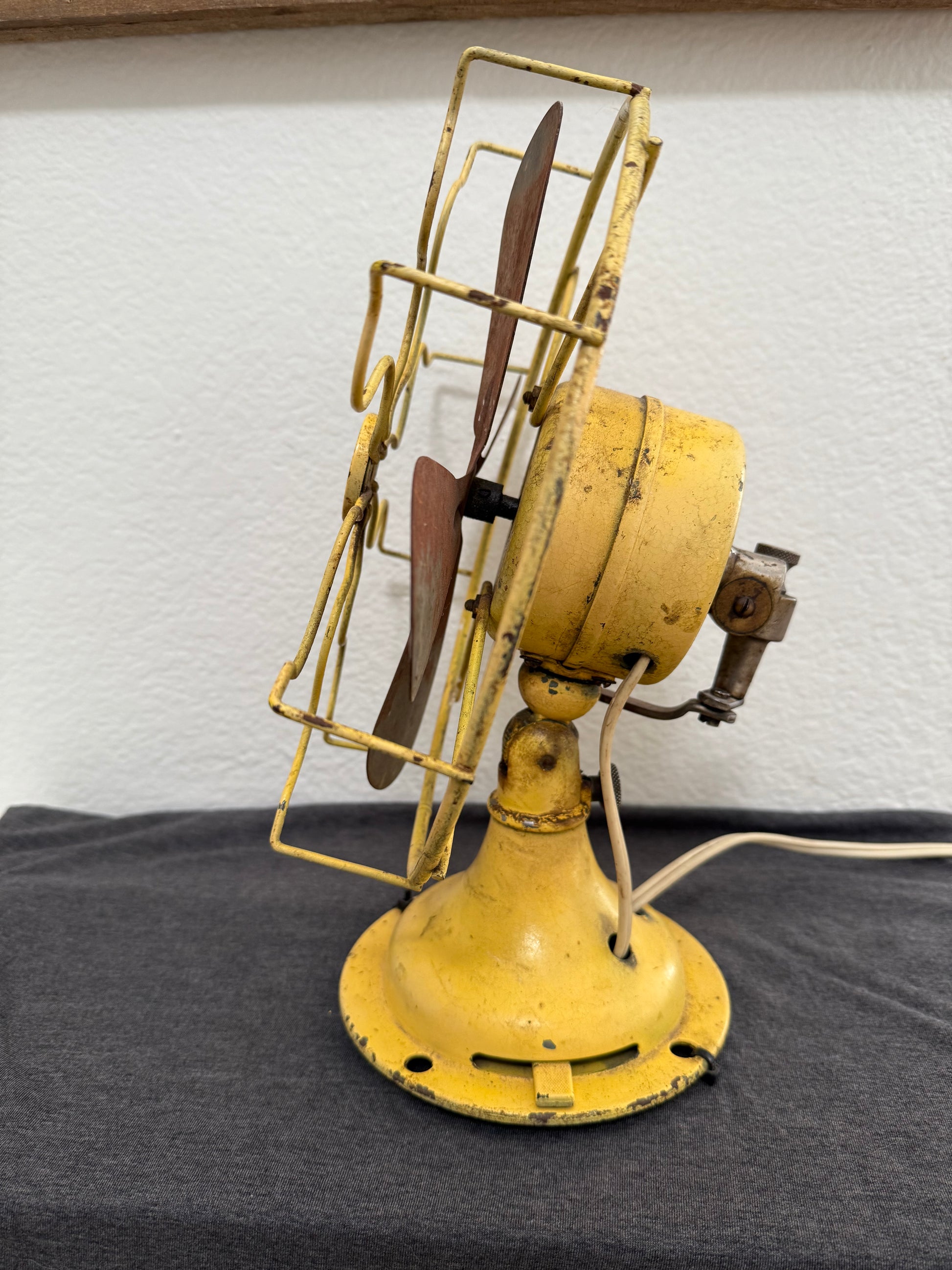 Vintage yellow fan against a white wall.