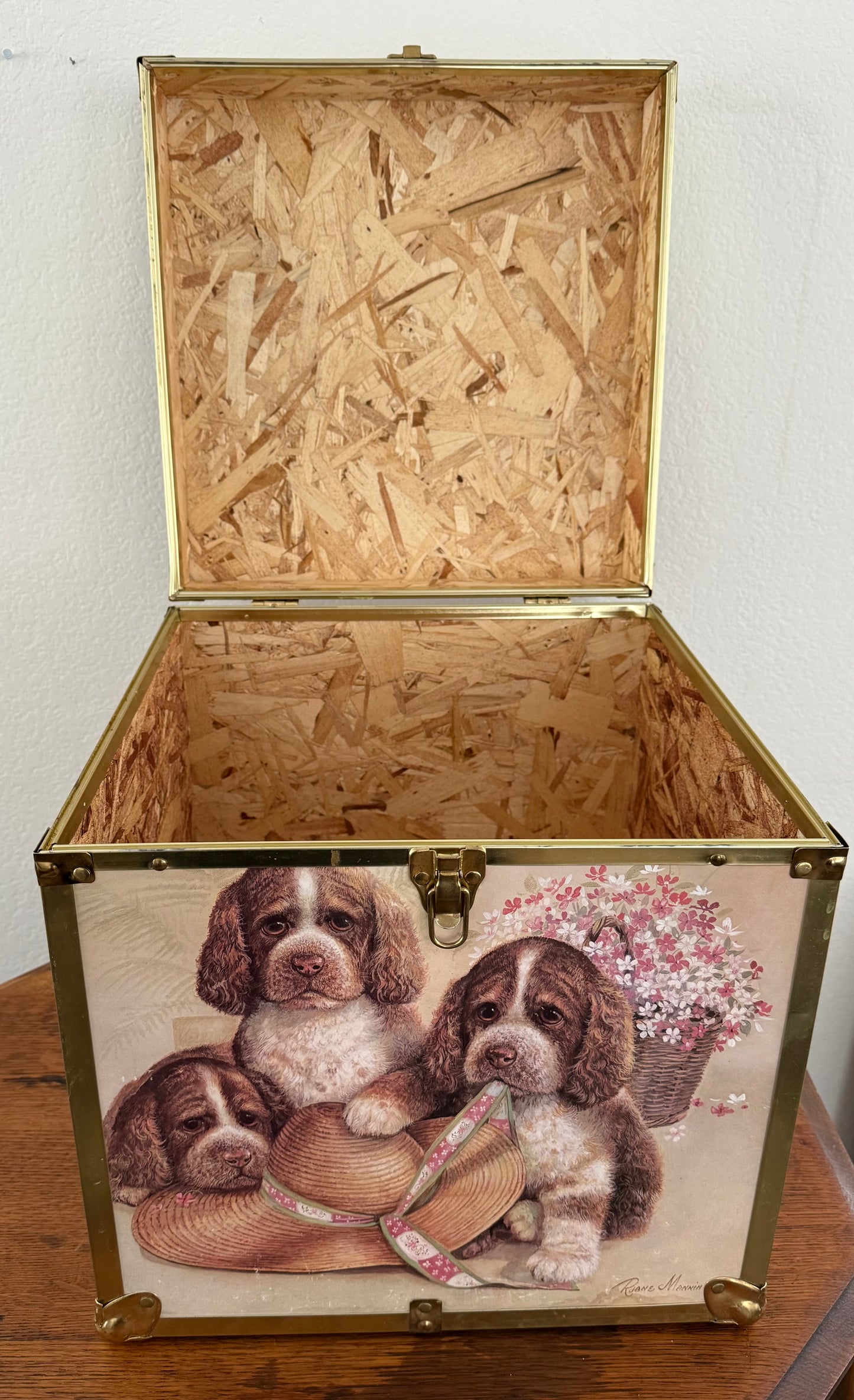 Wooden chest with decorative design of puppies and flowers on a wooden surface.