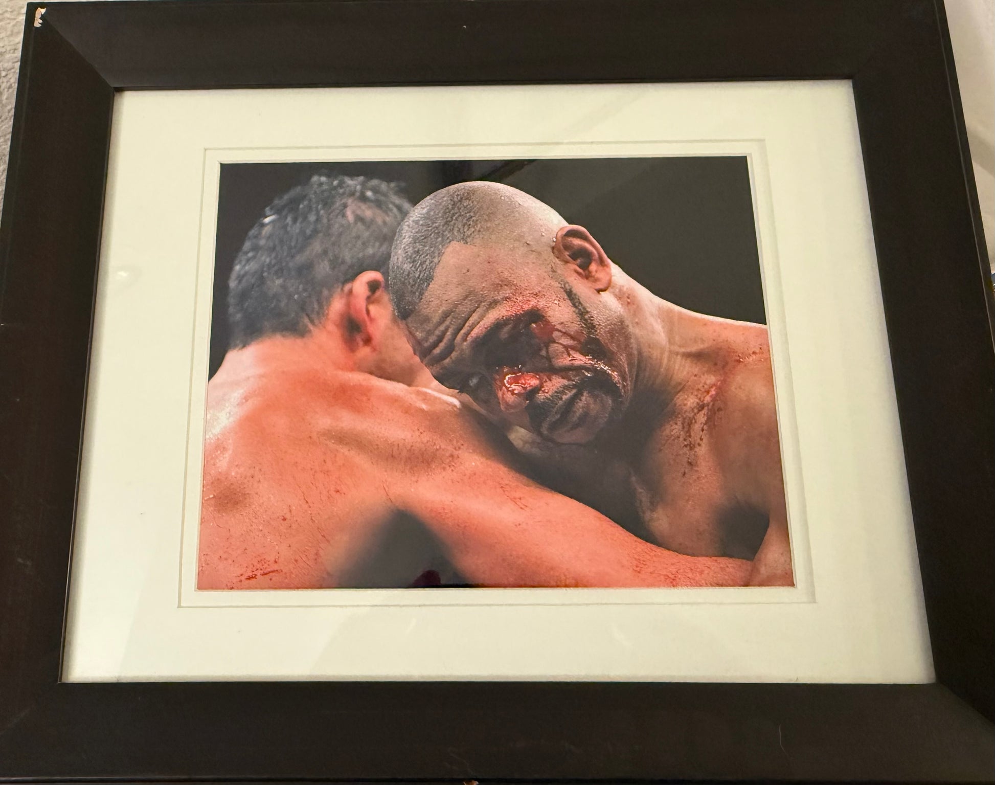 Framed photograph of two boxers in a close-up moment, with one boxer showing visible injuries.