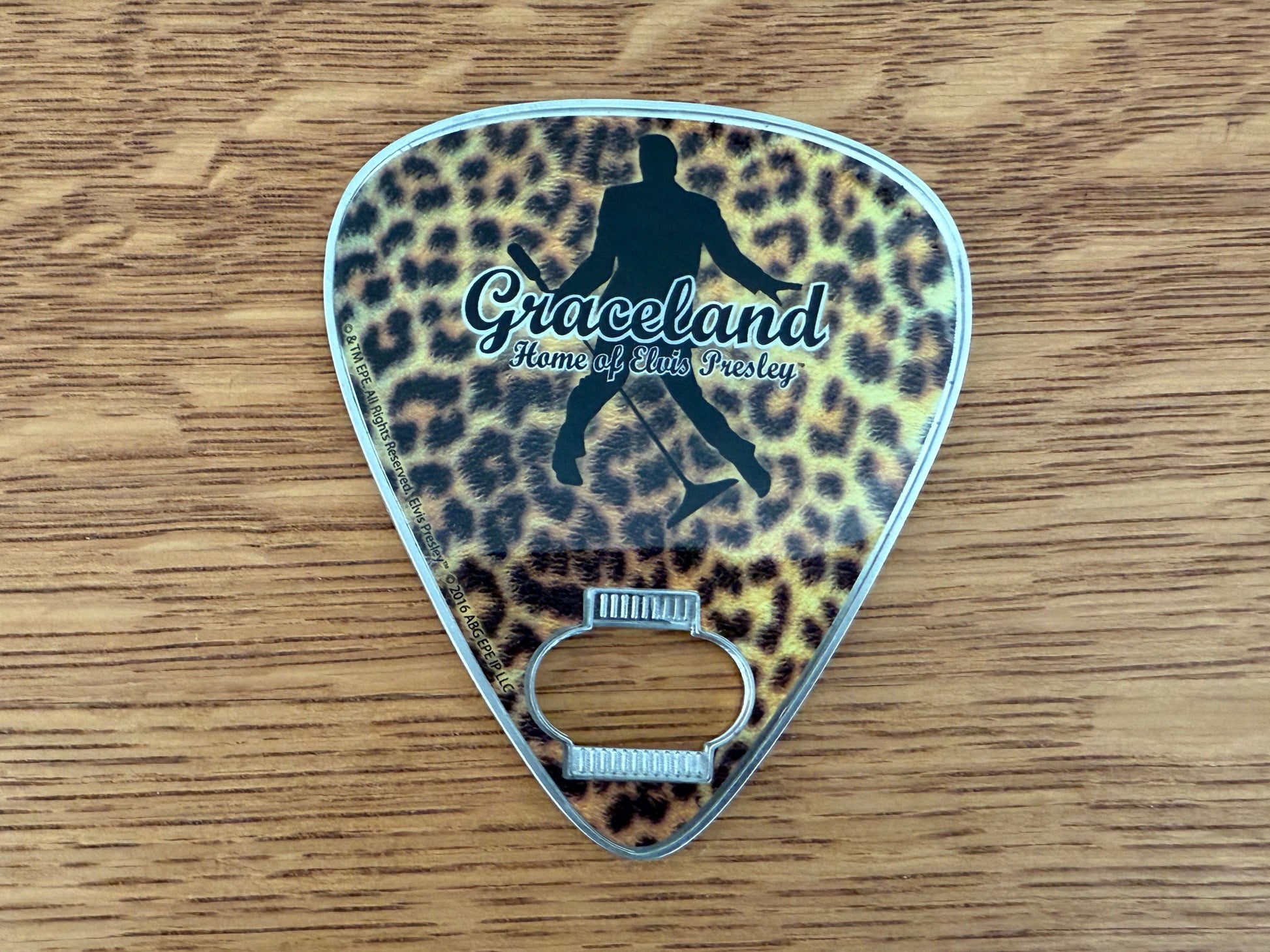 Leopard print bottle opener with 'Graceland' branding on a wooden surface
