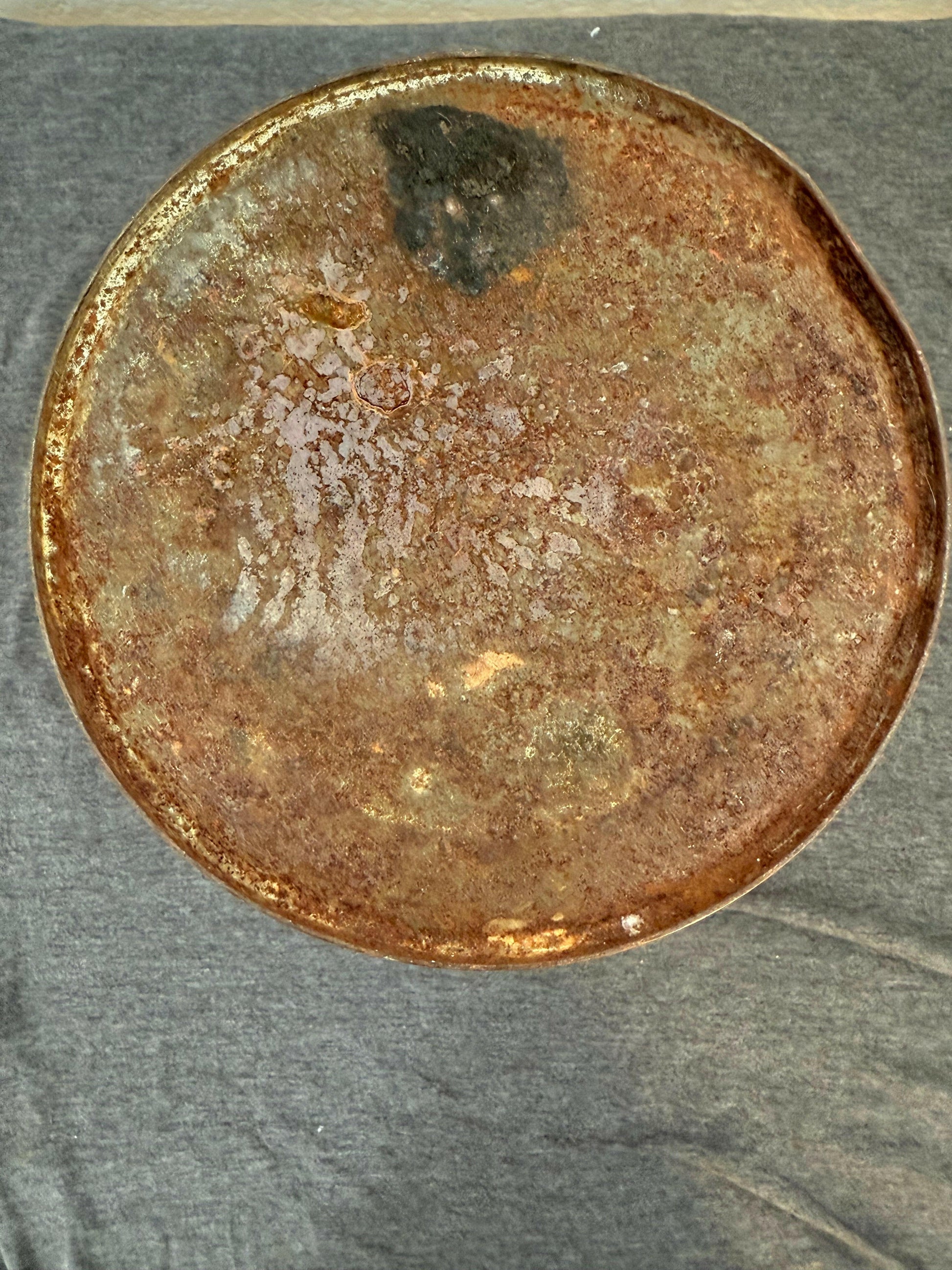 Rust-covered metal disc on a textured gray background