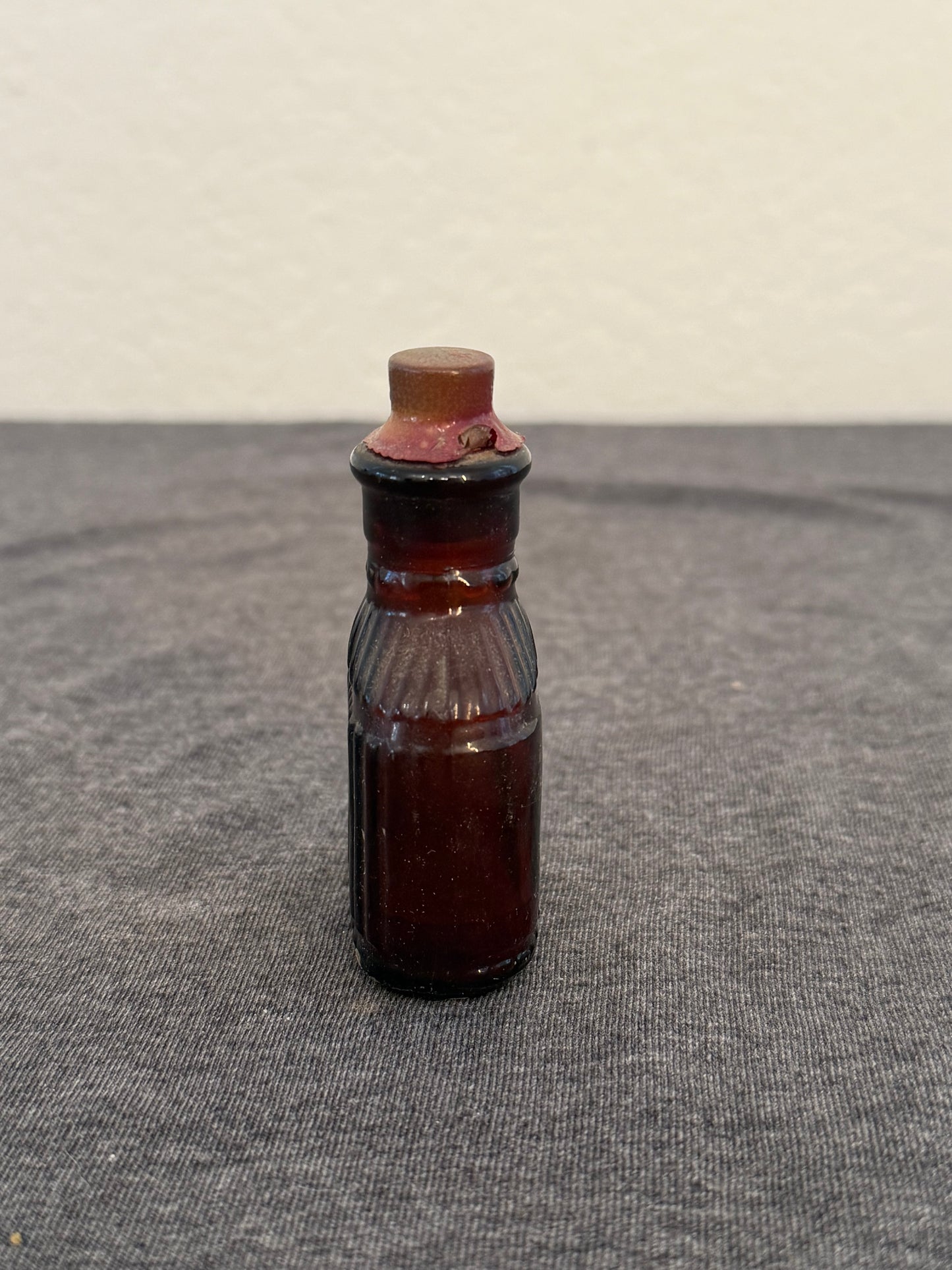Small brown bottle with a ribbed neck on a gray surface