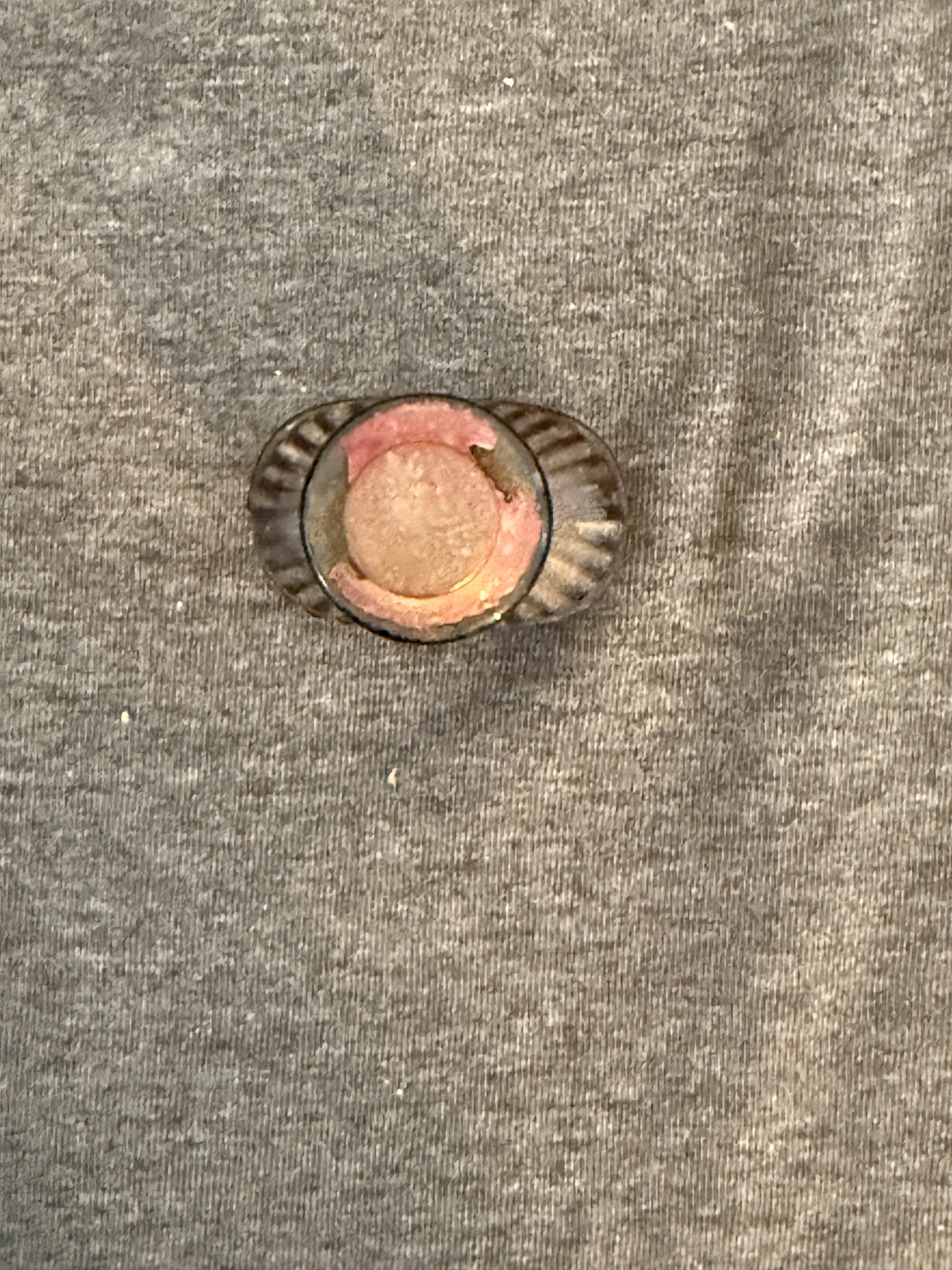 Small round object with a textured surface on a gray fabric background