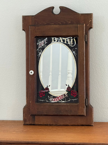 Wooden cabinet with decorative mirror on a white wall