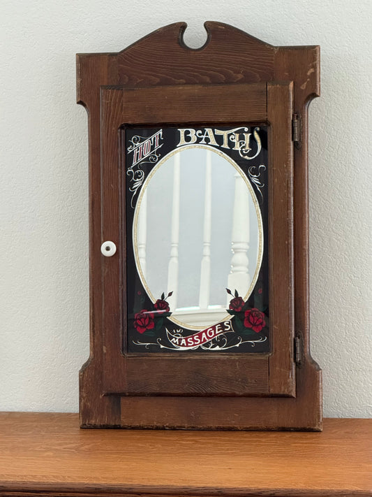 Wooden cabinet with decorative mirror on a white wall