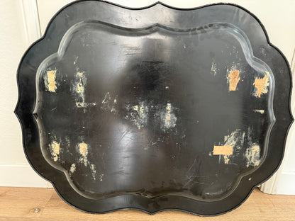 Black decorative tray with gold accents on a wooden surface