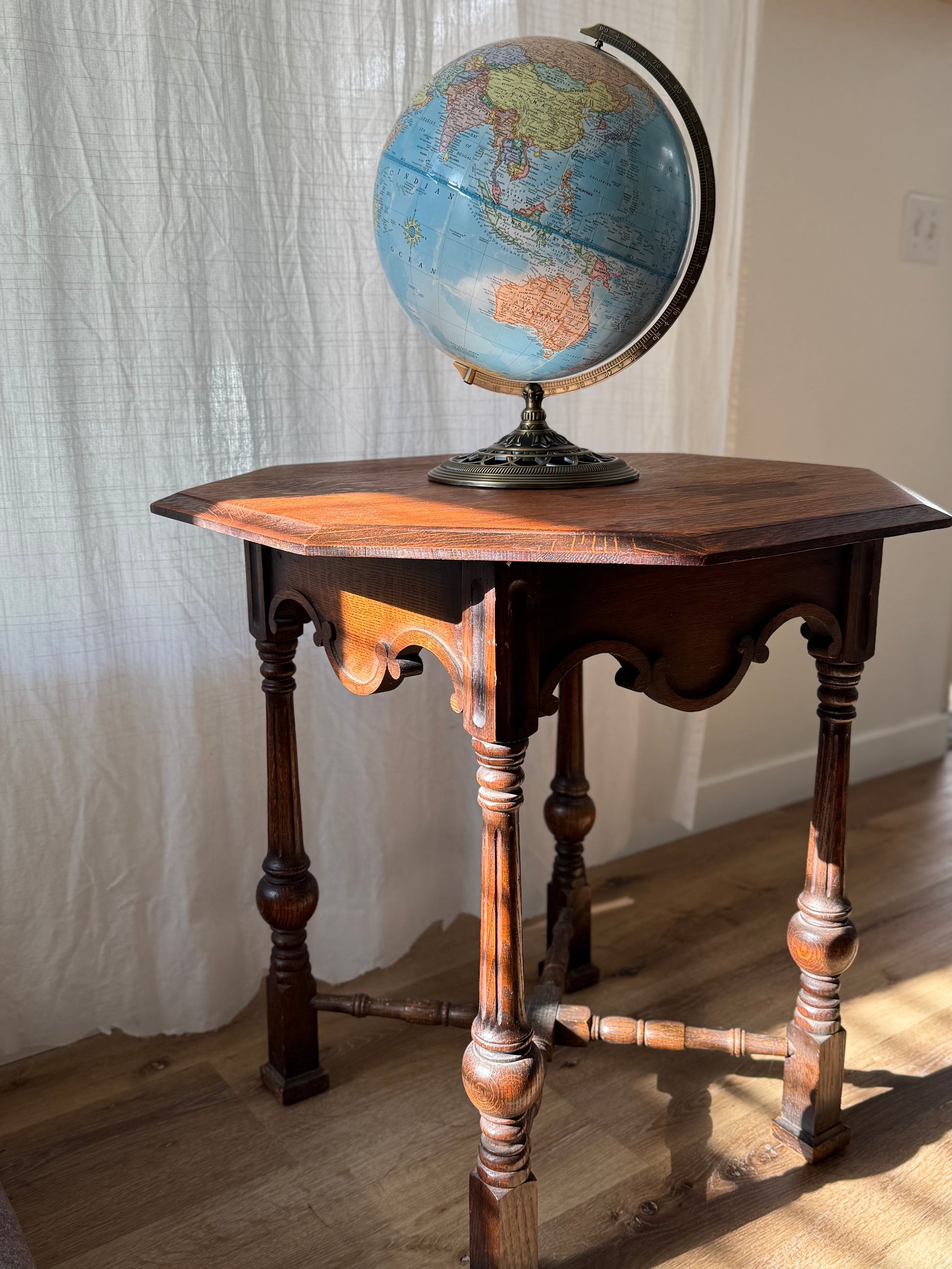 Antique wooden table with a world globe on a neutral background