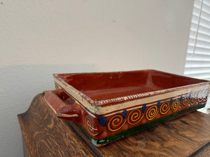 Decorative ceramic tray with handles on a wooden surface