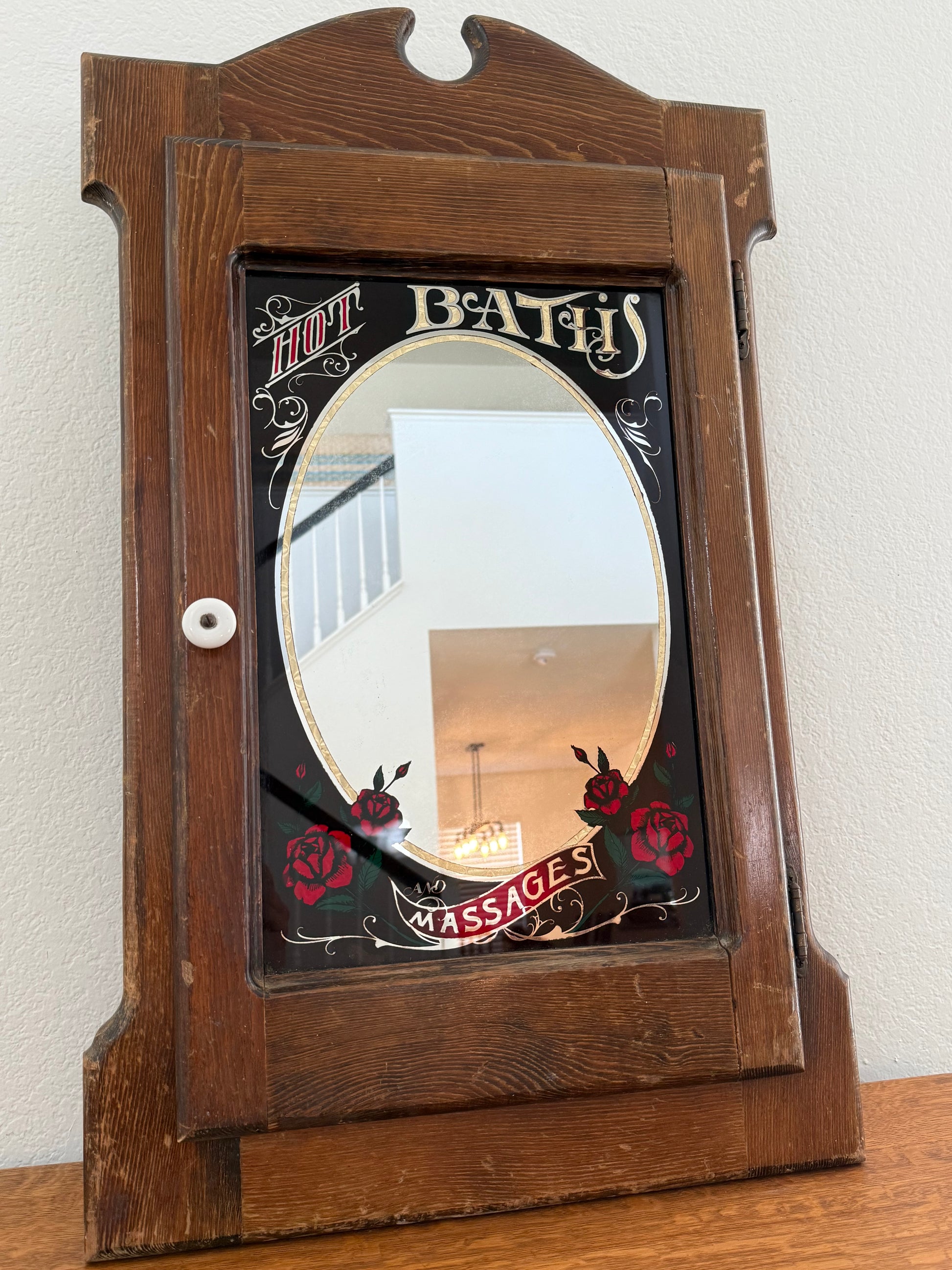 Wooden cabinet with decorative mirror on a white wall