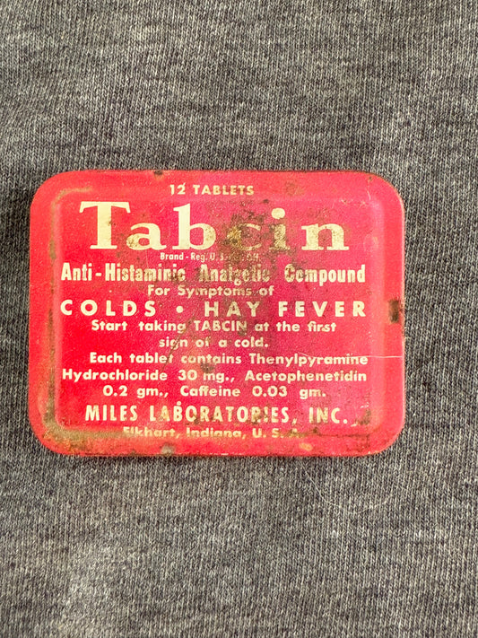 Vintage red tin labeled 'Tabin' for colds and hay fever on a gray textured background