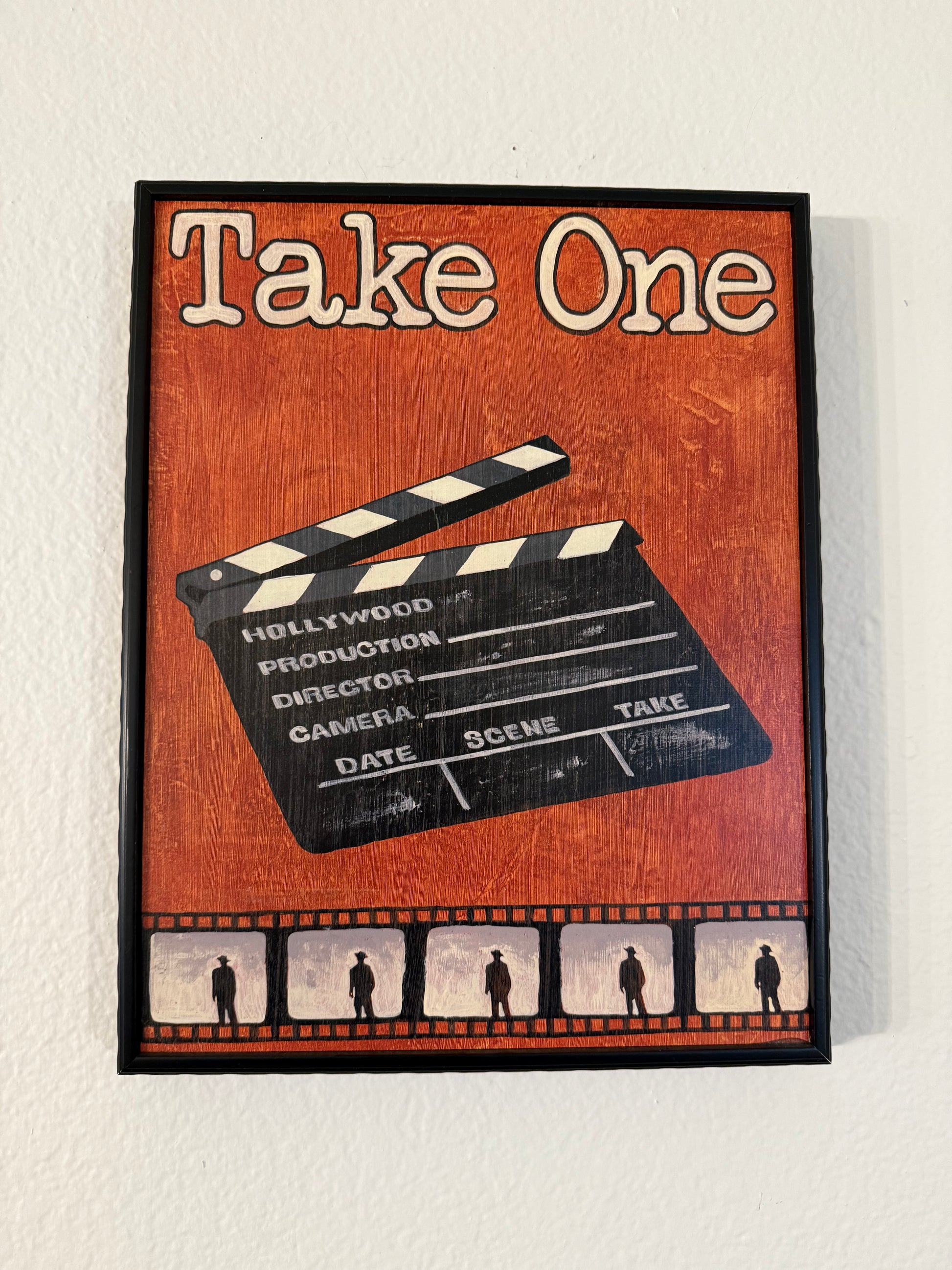 Decorative sign with clapperboard and filmstrip design on a wooden background