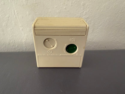Beige electronic device with buttons on a gray surface and white wall background