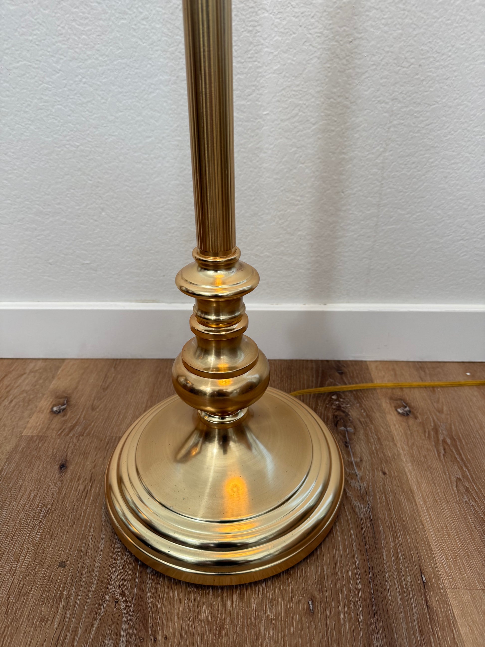 brass base on wood floor with a white wall background