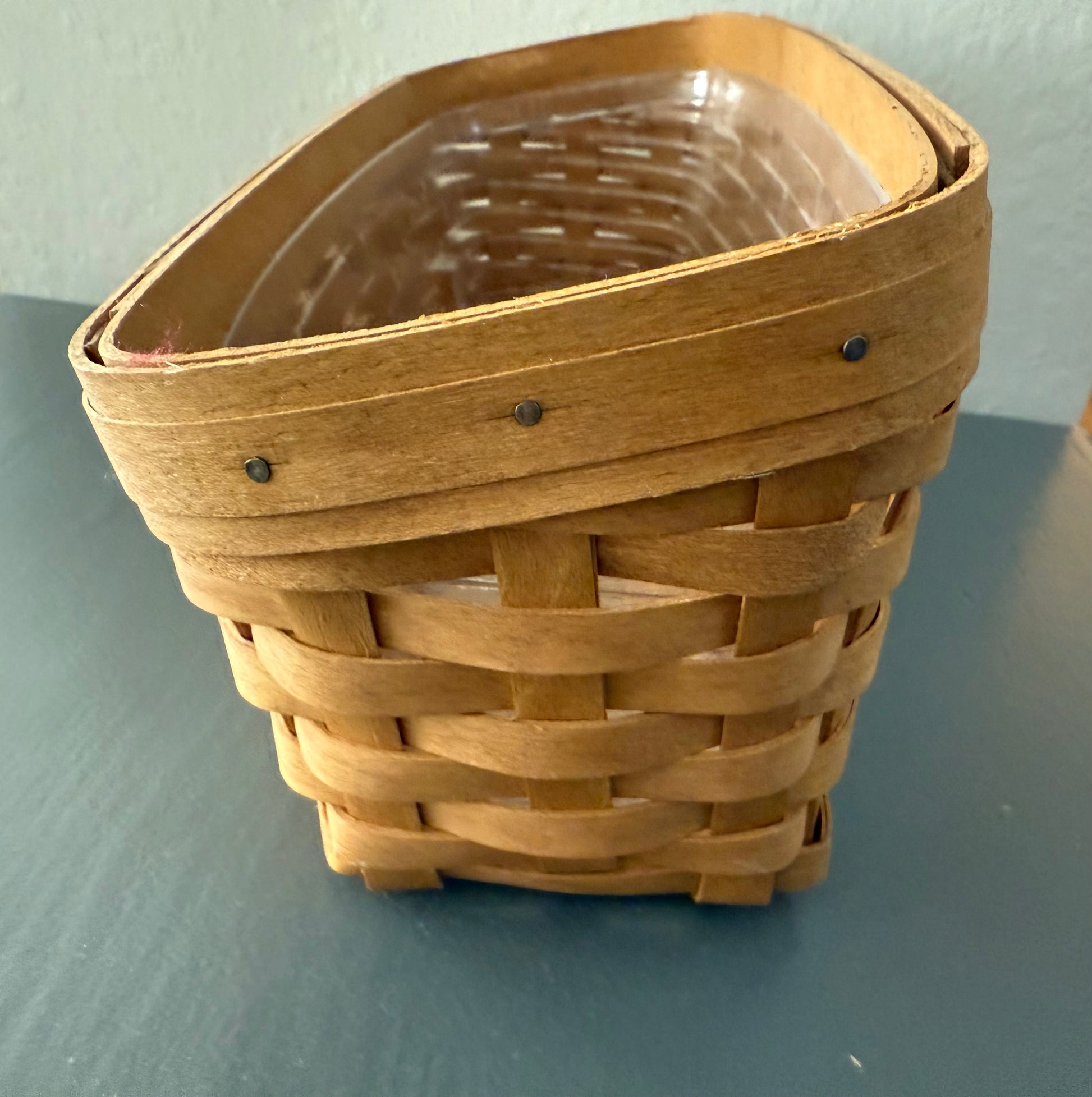 Wooden woven basket on a gray surface with a light blue background