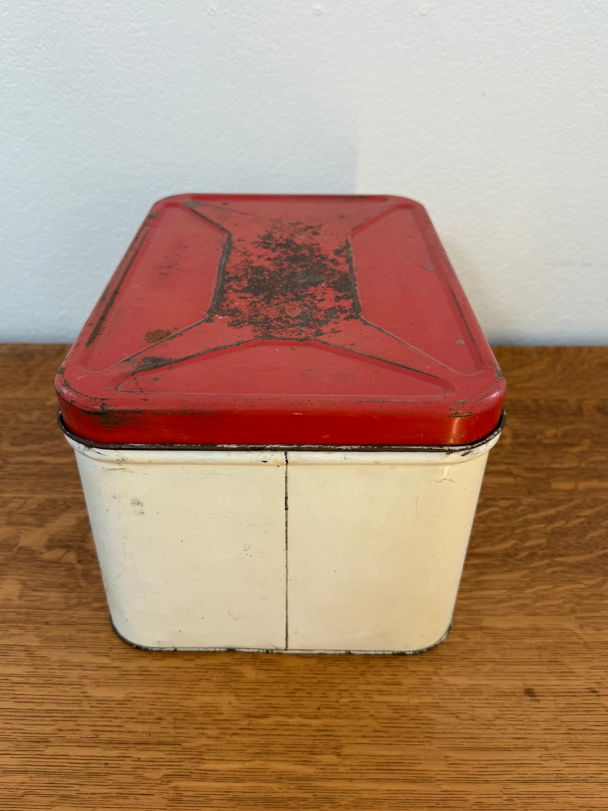 Vintage red and white metal box on a wooden surface