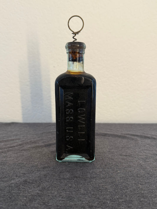 Vintage glass bottle with cork stopper and "Lowell Mass USA" written on it
