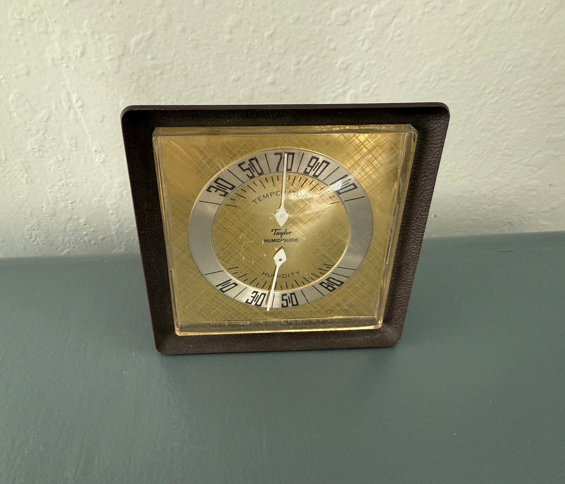 Vintage-style thermometer with brown frame on a gray surface