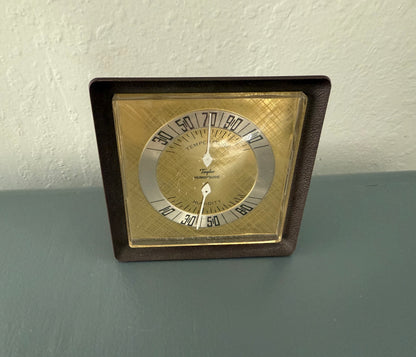 Vintage-style thermometer with brown frame on a gray surface