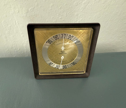 Vintage-style thermometer with brown frame on a gray surface