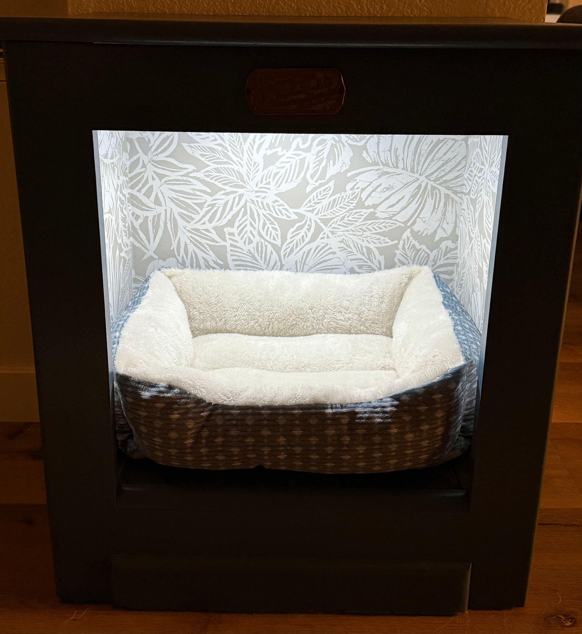 Pet bed inside a White Clad cabinet with floral pattern wallpaper.