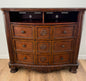 Wooden dresser with multiple drawers on a wooden floor.