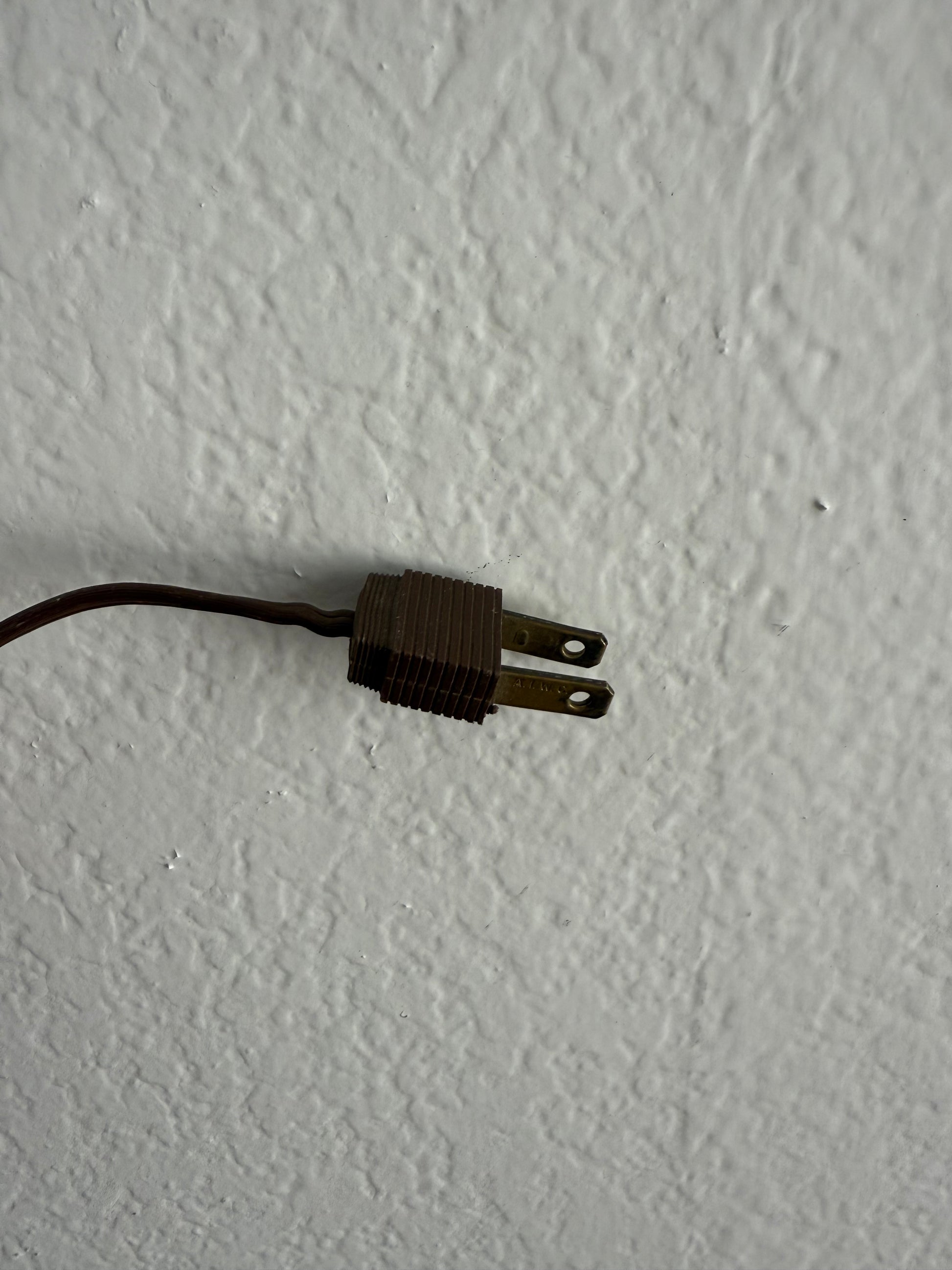 Old-style electrical plug on a textured white surface