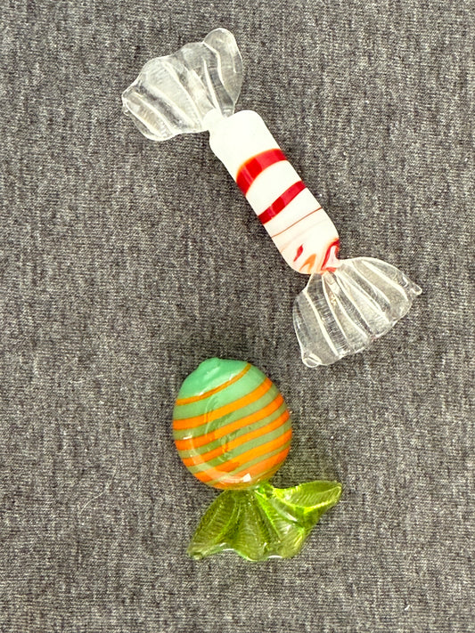 Two colorful glass candies on a gray surface
