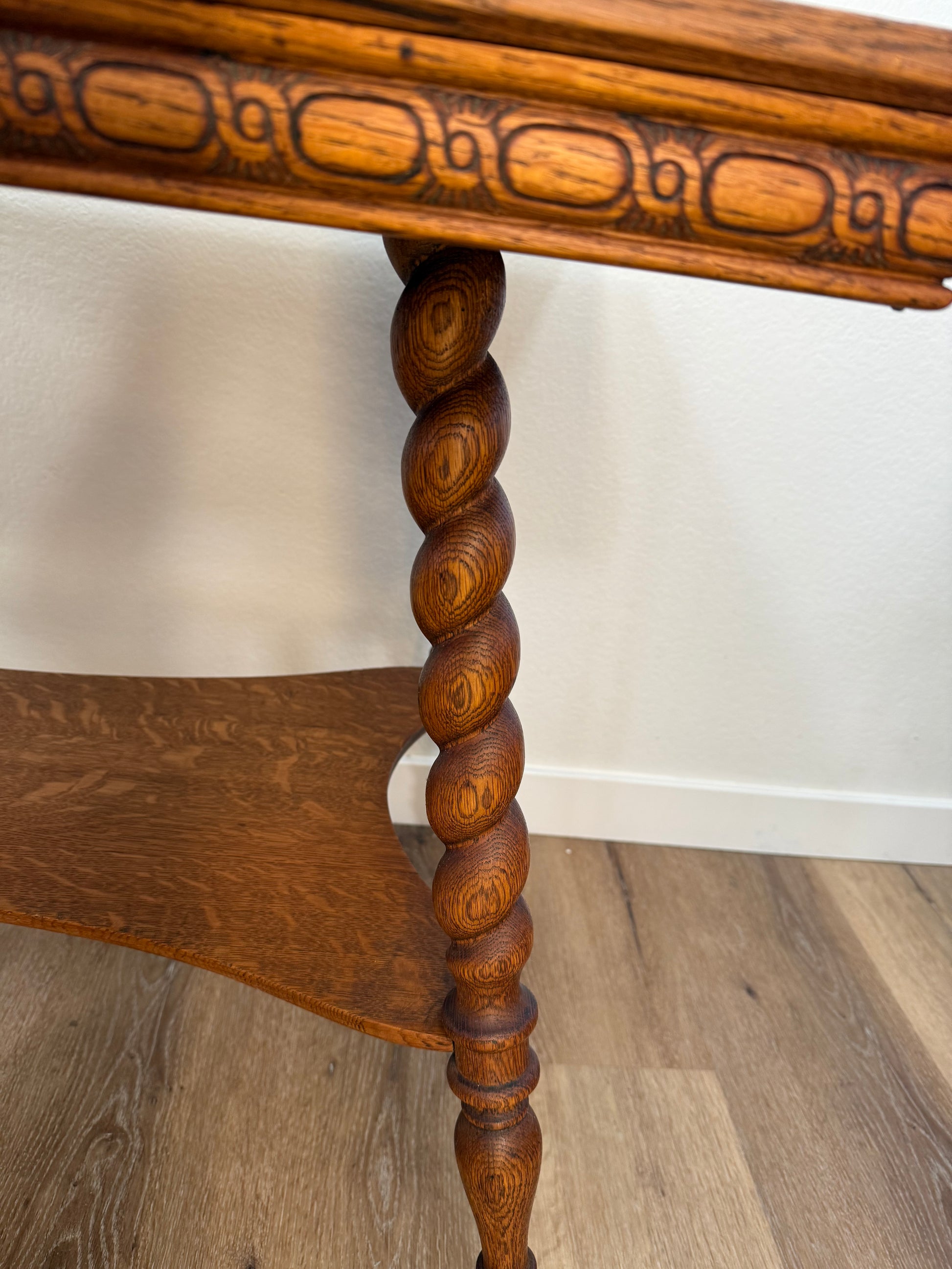 Wooden table with intricate carvings on a wooden floor.
