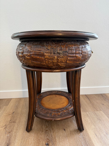 Round side table with a textured surface and a shelf on a wooden floor.