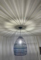 Woven pendant light fixture hanging from a textured ceiling