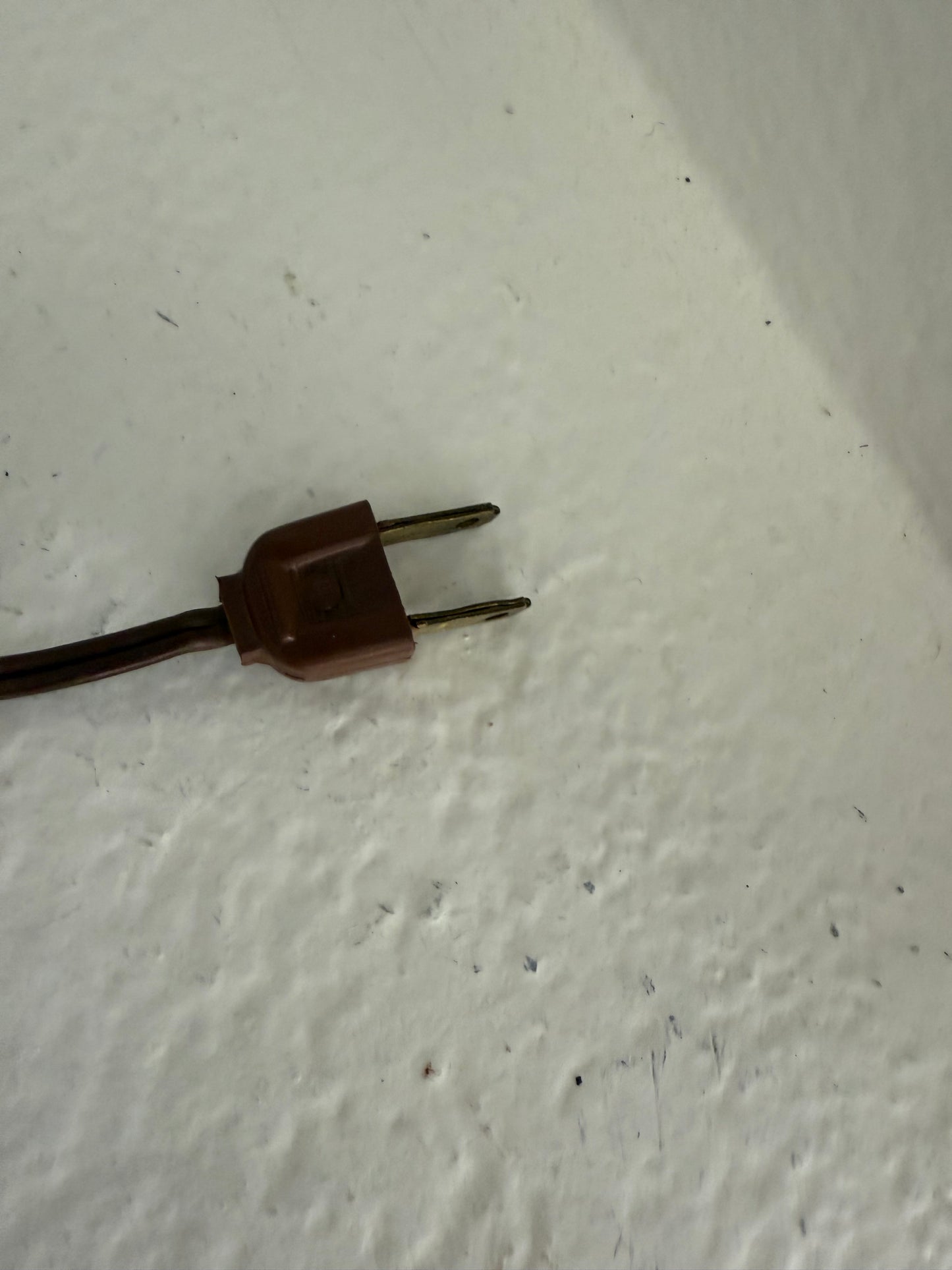 Brown electrical plug on a textured white surface