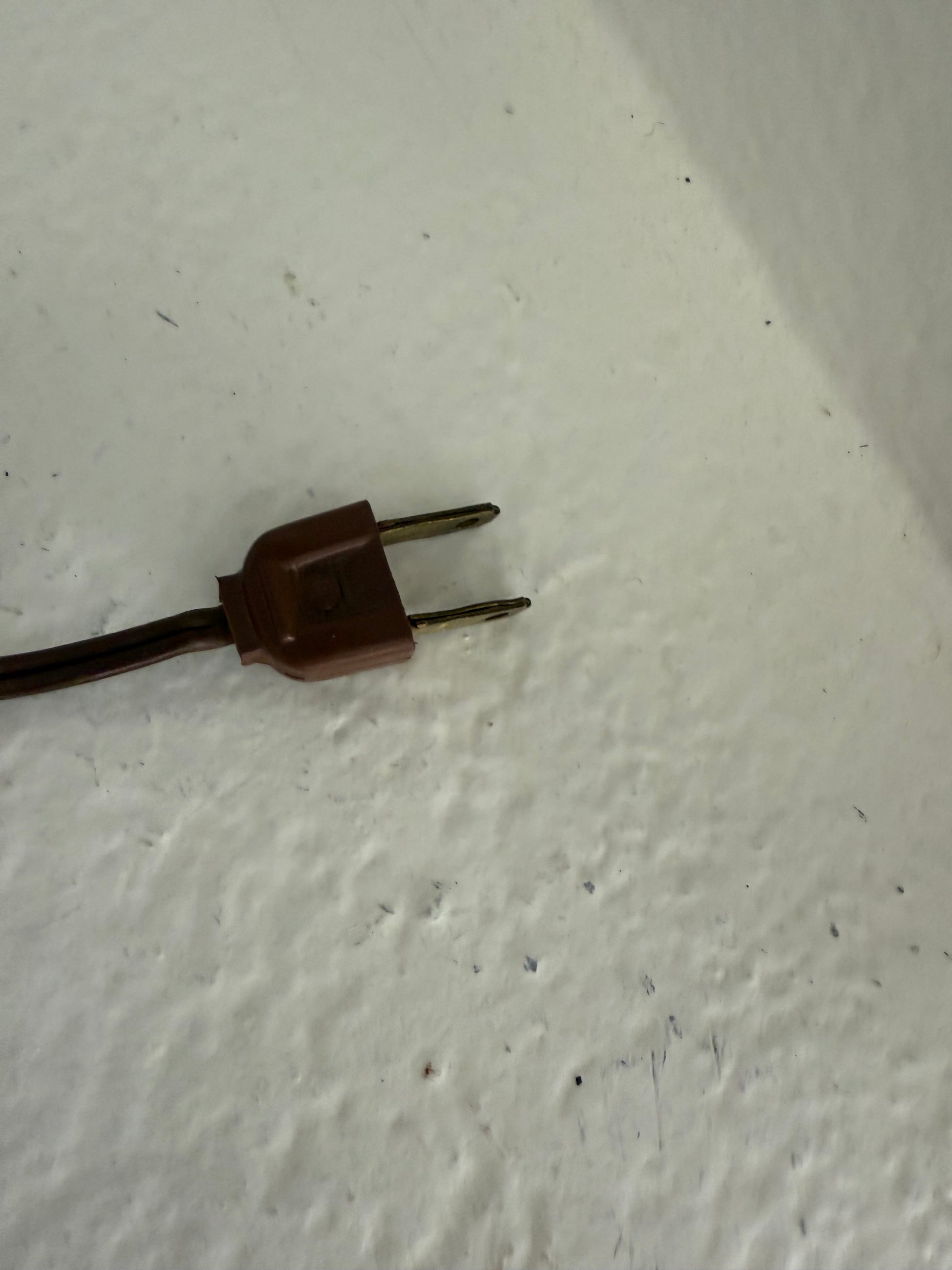 Brown electrical plug on a textured white surface
