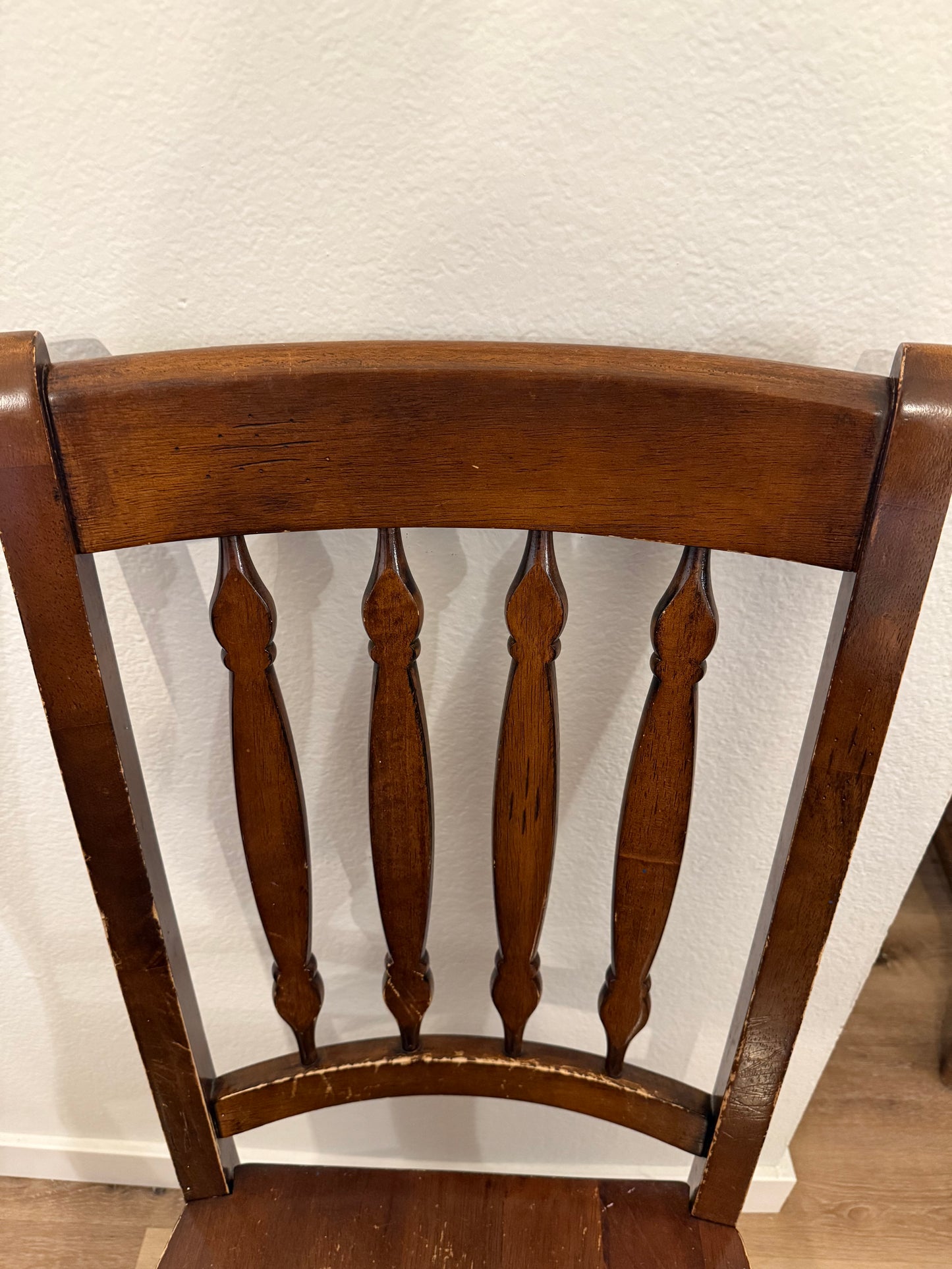 Wooden chair backrest against a white wall