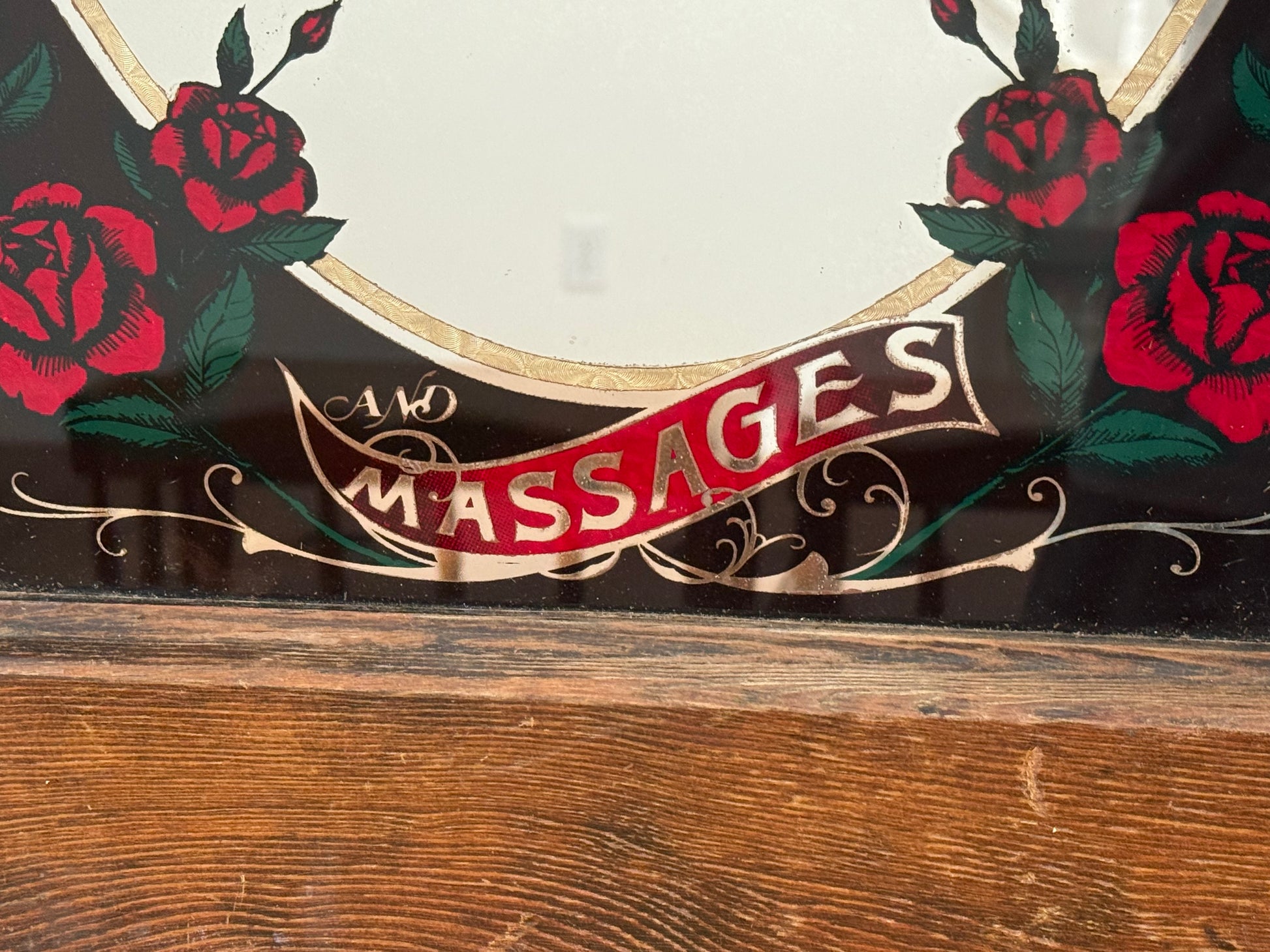 Decorative sign with roses and the word 'Massages' on a wooden surface.