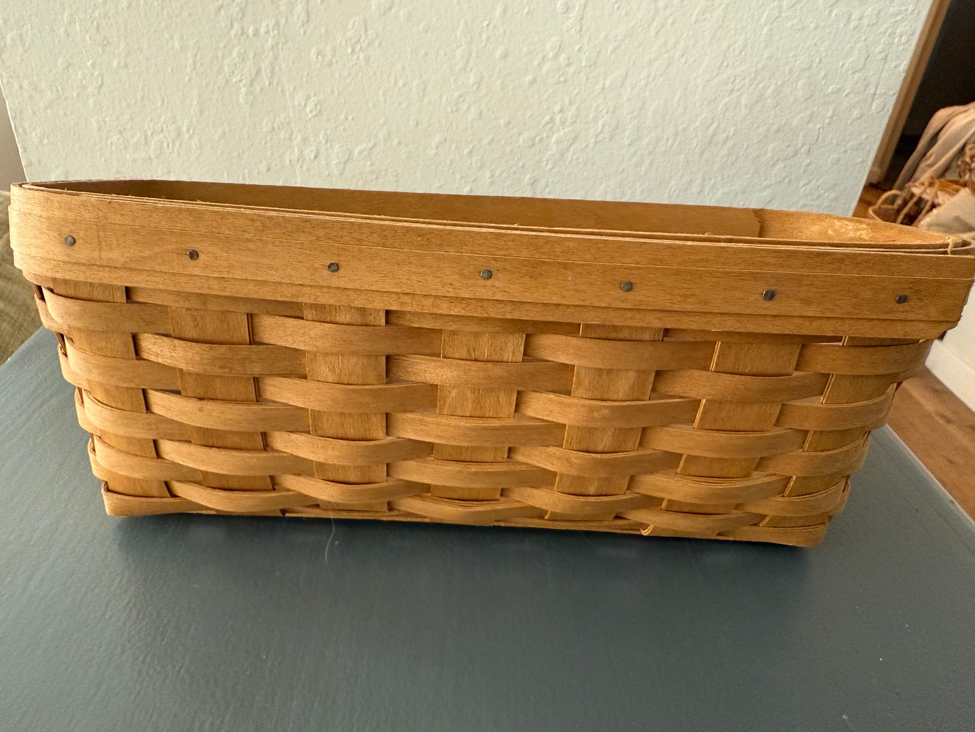 Woven wooden basket on a gray surface with a white wall background