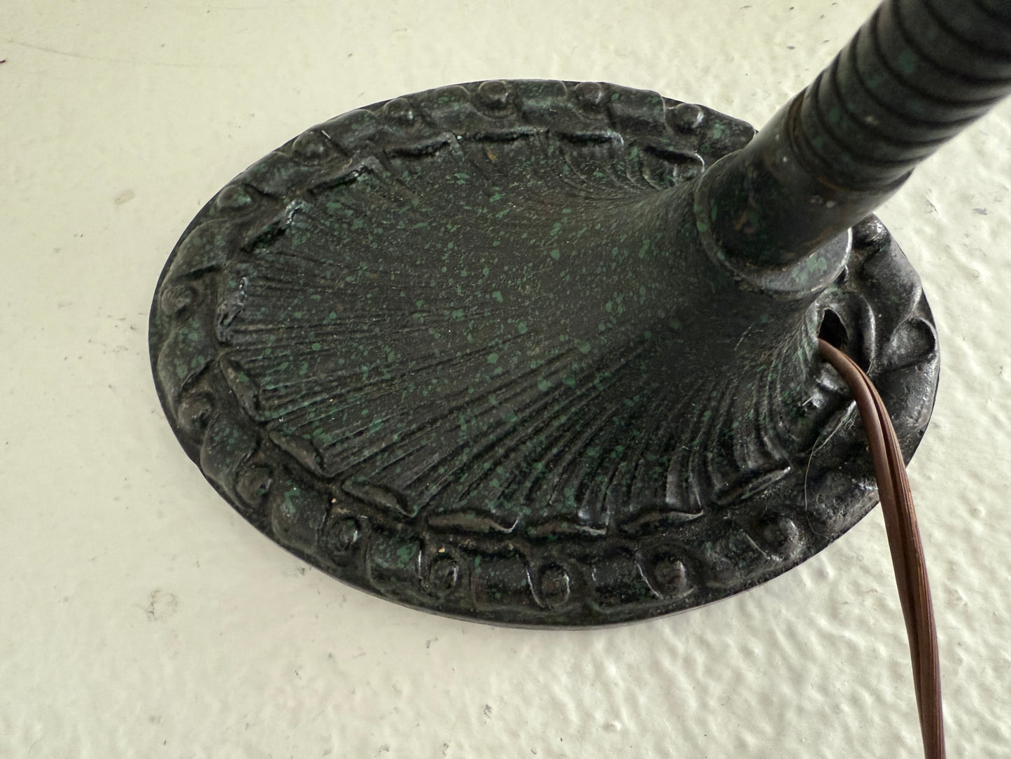 Decorative metal base of a lamp on a white wall