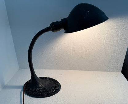 Black desk lamp on a white surface with a light blue wall background