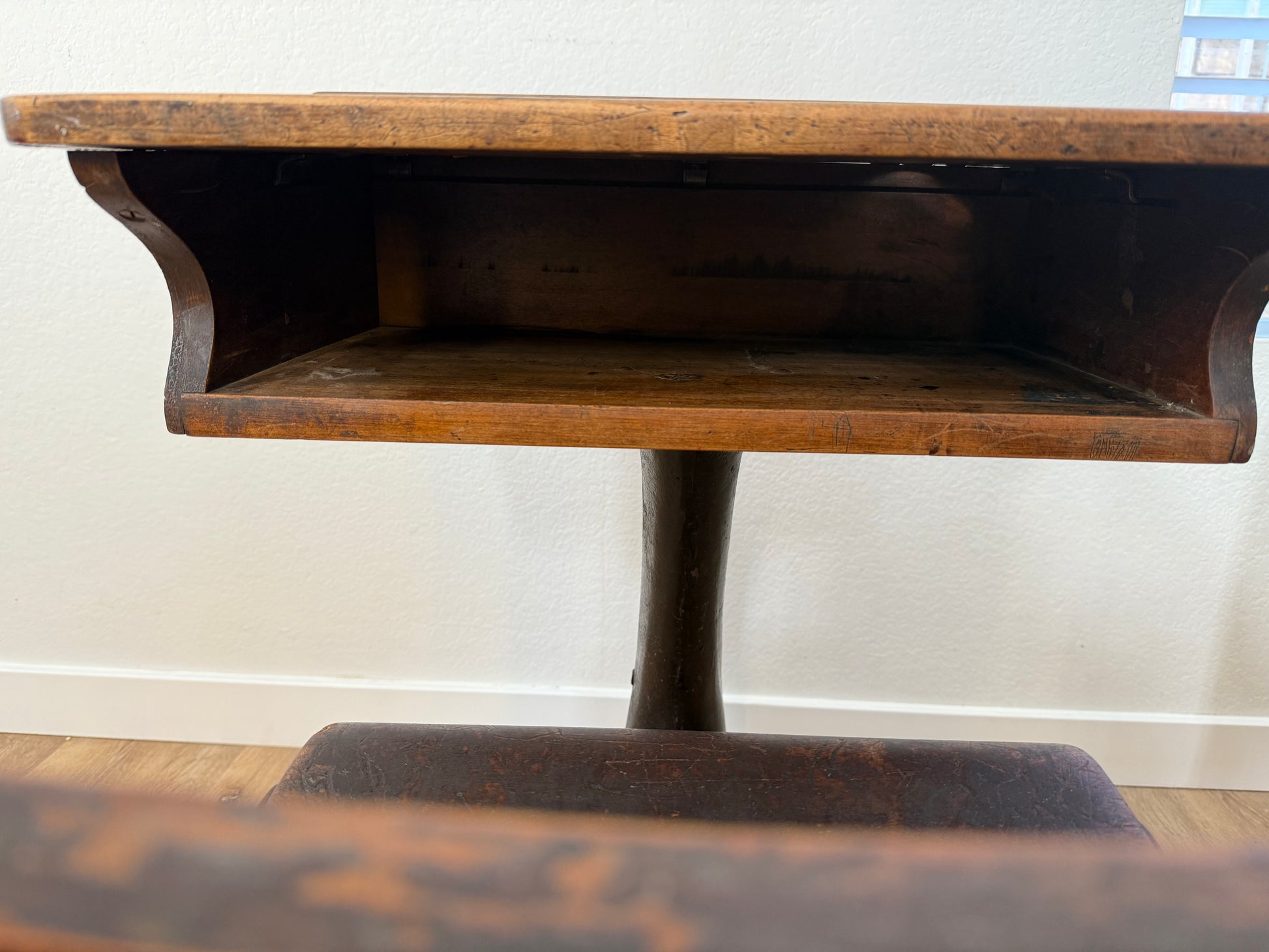 Wooden pedestal school desk with a white wall background