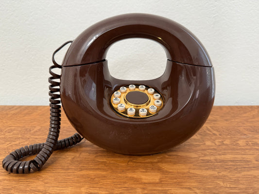 Brown retro telephone with a coiled cord on a wooden surface