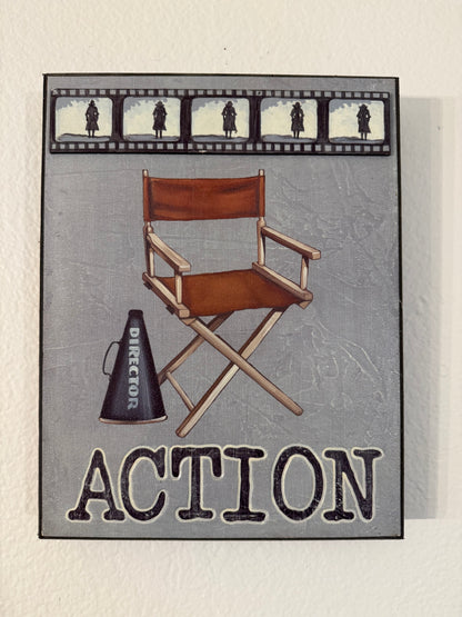 Movie prop set with director's chair, megaphone, and film strip on a gray background with 'ACTION' text.